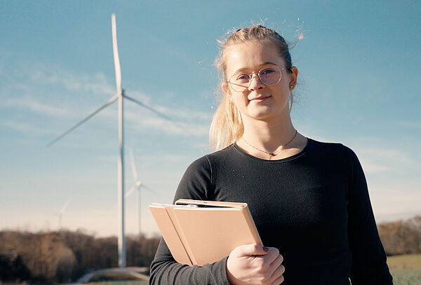 Energies + : une étudiante devant une éolienne